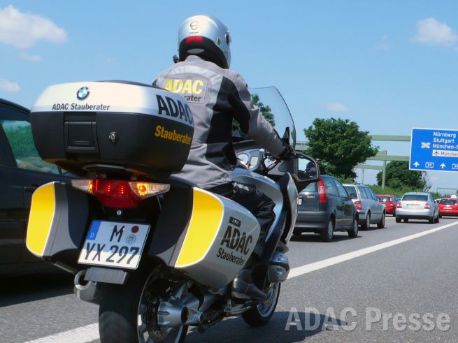 ADAC Stauberater fährt auf dem Motorrad am Stau auf der Autobahn vorbei